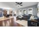 Open-concept living room featuring hardwood floors and a large blue sectional sofa under a ceiling fan at 5524 Shasta Daisy Pl, Land O Lakes, FL 34639