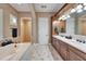 Bathroom with double sink vanity, soaking tub, patterned tile floor, and neutral paint at 5616 Seagrass Pl, Apollo Beach, FL 33572