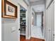 Hallway view of organized closet with white shelving, hardwood floors, leading to bathroom with patterned tile at 5616 Seagrass Pl, Apollo Beach, FL 33572