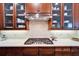 Close up of the kitchen with cooktop, quartz countertops, tile backsplash, and glass cabinets at 5616 Seagrass Pl, Apollo Beach, FL 33572
