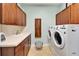 Well-organized laundry room features wooden cabinets, white washer, and dryer at 5616 Seagrass Pl, Apollo Beach, FL 33572