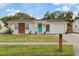 Charming single-story home featuring a well-manicured lawn, a bright teal door, and modern siding accents at 6339 S Lansdale Cir, Tampa, FL 33616