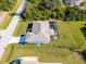 An aerial view displaying the home's backyard pool, neatly trimmed lawn, and driveway leading to the garage at 7235 Peacock Ln, Englewood, FL 34224