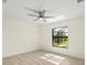 Bright bedroom featuring wood-look floors, ceiling fan, and a window overlooking the yard at 7235 Peacock Ln, Englewood, FL 34224