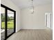Open dining room with a modern light fixture, tile flooring, and a sliding glass door with a green lawn view at 7235 Peacock Ln, Englewood, FL 34224