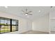 Bright living room with large window, ceiling fan, and light gray wood-look floors at 7235 Peacock Ln, Englewood, FL 34224