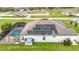 An aerial view highlighting the solar panels on the roof and the screened pool area at 9820 Monaghan St, Thonotosassa, FL 33592