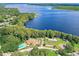 Panoramic aerial view of a lakefront property featuring a community pool, green spaces, and mature trees at 2297 Lark E Cir # E, Palm Harbor, FL 34684