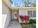 Close up of the main entrance with vibrant pink plants and a brick walkway leading to the glass front door at 1751 Sutton Pl, Dunedin, FL 34698