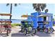 Several surrey bikes are parked in front of a bright blue store near the water at 25 Windrush Bay Dr # 25, Tarpon Springs, FL 34689