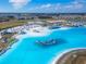 An aerial view showcases a vibrant community lagoon with sandy beaches and an inflatable water park at 31999 Surfton Knot Ct, San Antonio, FL 33576