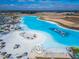 Aerial view of a lagoon with white sand, recreational waterpark, lounge areas, and umbrellas at 31999 Surfton Knot Ct, San Antonio, FL 33576