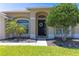 Close-up of the front entrance, showcasing a decorative wreath, mature landscaping, and arched windows at 3233 Russett Pl, Land O Lakes, FL 34638