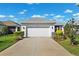 Two car garage with a large driveway and manicured landscaping at 3579 Sweet Mabolo St, Wesley Chapel, FL 33543