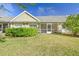 Exterior view of the back of the property showcasing a screened-in patio and grassy yard at 3638 Trafalgar Way # 103, Palm Harbor, FL 34685