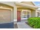Inviting front entrance with a charming red door, attached garage, and manicured landscaping at 3638 Trafalgar Way # 103, Palm Harbor, FL 34685