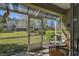 Covered and screened porch features outdoor seating and a view of landscaped backyard at 3638 Trafalgar Way # 103, Palm Harbor, FL 34685