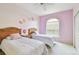 Charming bedroom with twin beds, arched window, and playful butterfly accents on the lavender and cream-colored walls at 4410 Sawgrass Dr, Palm Harbor, FL 34685