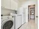 Bright laundry area featuring a washer, dryer, refrigerator, white cabinets, and access to a bathroom at 4410 Sawgrass Dr, Palm Harbor, FL 34685