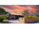 View of a modern home with a wooden fence set against a vibrant sunset sky, enhancing its curb appeal at 4430 11Th N Ave, St Petersburg, FL 33713