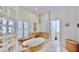 Luxury bathroom featuring travertine tile, glass block shower, and a soaking tub with tiled surround at 615 Islebay Dr, Apollo Beach, FL 33572