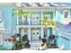 Close-up view of the entrance of the light blue home with a balcony, pillars and tropical landscaping at 615 Islebay Dr, Apollo Beach, FL 33572