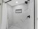 Modern walk-in shower with white marble-style tiles, black fixtures, and a shower niche at 7623 Radcliffe Cir # A101, Port Richey, FL 34668