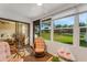 Enclosed sunroom with wicker furniture, views of the landscaped yard, and access to the bedroom at 7623 Radcliffe Cir # A101, Port Richey, FL 34668