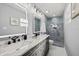 A modern bathroom with double sinks, marble countertops, illuminated mirrors, and a glass-enclosed shower at 8501 N Alaska St, Tampa, FL 33604