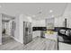 A spacious kitchen with stainless steel appliances, modern white cabinets, and a view of the refrigerator and hallway at 8501 N Alaska St, Tampa, FL 33604