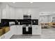 A contemporary kitchen with stainless steel appliances and sleek black countertops, with view to dining area at 8501 N Alaska St, Tampa, FL 33604