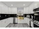 A modern kitchen featuring white cabinets, black countertops and backsplash, and a gold-colored sink at 8501 N Alaska St, Tampa, FL 33604