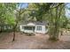 Cozy white cottage-style home with a screened porch, nestled amongst trees on a large leafy lot at 9025 Gronde Ave, Brooksville, FL 34601