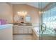 Bright bathroom with double vanity, soaking tub, and glass-enclosed shower with leafy patterned curtain at 10222 Woodford Bridge St, Tampa, FL 33626