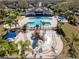 Aerial view of community pool and splash pad, complete with seating, umbrellas, and a clubhouse at 11202 Wembley Landing Dr, Lithia, FL 33547