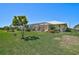 Backyard view featuring lush lawn, landscaping, and screened-in pool area at 12 Medalist Ter, Rotonda West, FL 33947