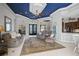 Open-concept living room with tile floor, leading to a breakfast bar and kitchen, featuring a stylish blue ceiling at 12 Medalist Ter, Rotonda West, FL 33947