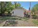Back of house featuring partial lawn, mature plantings, and small deck at 12519 Cambridge Ave, Tampa, FL 33624