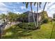 Beautifully landscaped backyard with a screened-in lanai surrounded by mature palm trees and lush green lawn at 137 11Th E St, Tierra Verde, FL 33715