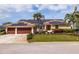 Beautiful single-story home with a well-manicured lawn, mature landscaping, and solar panels on the roof at 137 11Th E St, Tierra Verde, FL 33715