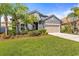 Charming single-Gathering home featuring a manicured lawn, complemented by mature palm trees, and a two-car garage at 1435 Montgomery Bell Rd, Wesley Chapel, FL 33543