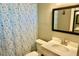 Clean bathroom with white vanity and framed mirror, complemented by a shower with a blue floral curtain at 1509 Lemon St, Clearwater, FL 33756