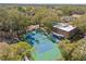 Aerial view of the tennis court, playground, and community amenities in a wooded setting at 1562 Nantucket Ct # 1208, Palm Harbor, FL 34683