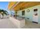Outdoor kitchen with a marble countertop, grill, and exterior door with ceiling fan, perfect for entertaining at 15904 Redington Dr, Redington Beach, FL 33708