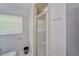 Bright bathroom featuring tiled walk-in shower, modern fixtures, and frosted glass door at 2708 De Montmollin Rd, Plant City, FL 33565