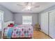 Bright bedroom featuring wood floors, ceiling fan, closet, and colorful comforter over white frame bed at 2708 De Montmollin Rd, Plant City, FL 33565