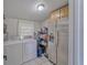 Bright laundry room with washer, dryer, refrigerator, upper cabinets, shelves, and tile floor at 2708 De Montmollin Rd, Plant City, FL 33565