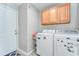 Laundry room featuring a white washer and dryer, upper cabinets and a white door at 3115 Bent Creek Dr, Valrico, FL 33596