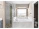 Bathroom with tiled shower, white tub, and a window at 3654 Beneraid St, Land O Lakes, FL 34638