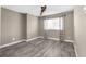 Neutral bedroom with grey hardwood flooring, window, and ceiling fan at 3654 Beneraid St, Land O Lakes, FL 34638